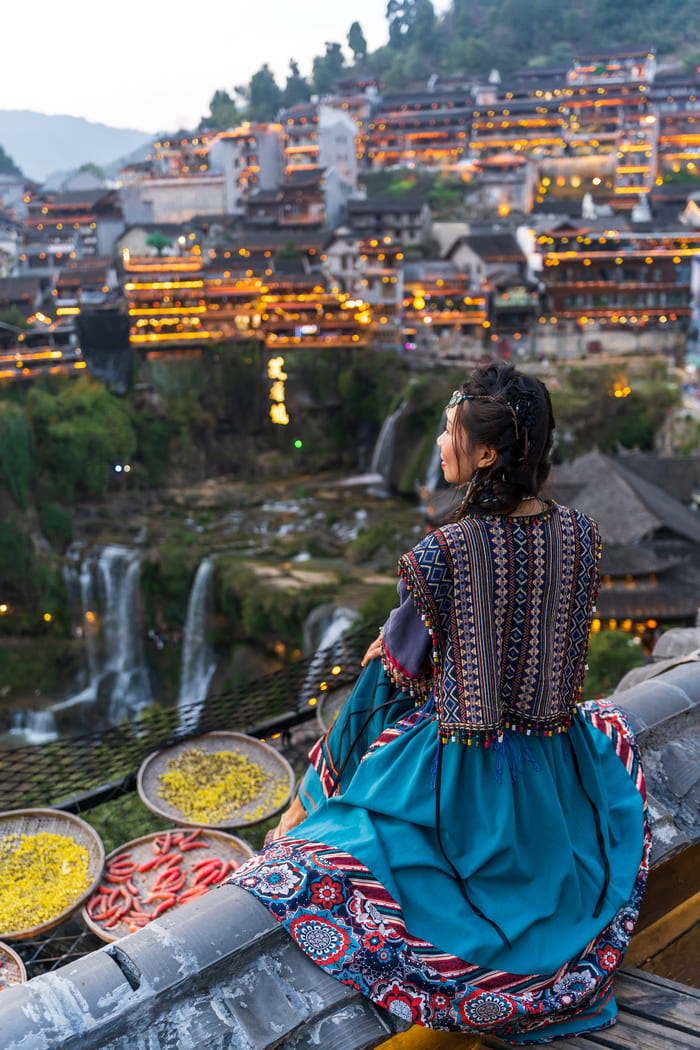 Mujer sentada observando la ciudad Lijiang
